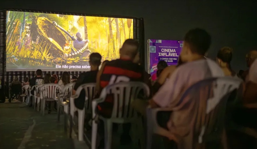 Cinema Inflável em Maricá transforma orla em cinema gratuito Cinema ao ar livre com famílias assistindo filme no Parque Nanci em Maricá